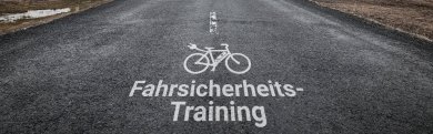 Weißer Schriftzug Fahrsicherheits-Training mit Radsymbol auf Asphalt