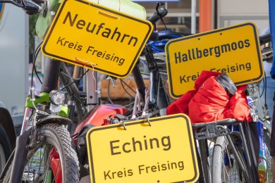 Drei Fahrräder mit Ortstafeln der Gemeinden Neufahrn, Eching und Hallbergmoos
